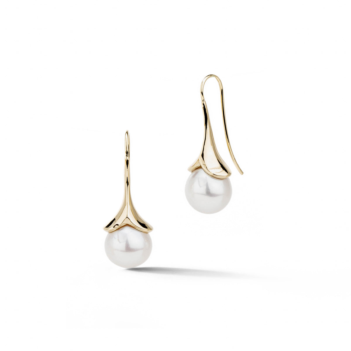 14k yellow gold lily-shaped drop earrings with large round white freshwater pearls on a sage green background, by deJonghe Original Jewelry