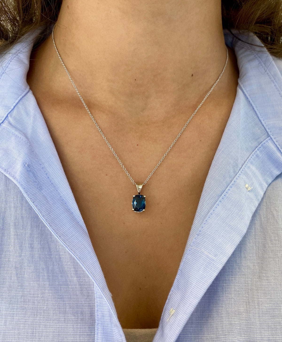 14k white gold pendant with prong-set cushion-cut London blue topaz and fleur de lis bail detail