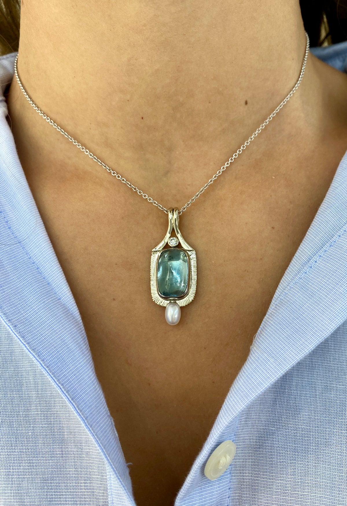 14k and 18k white gold pendant featuring a 7.82ct aquamarine cabochon in a hand-forged textured bezel, accented by a bezel-set diamond and freshwater pearl drop