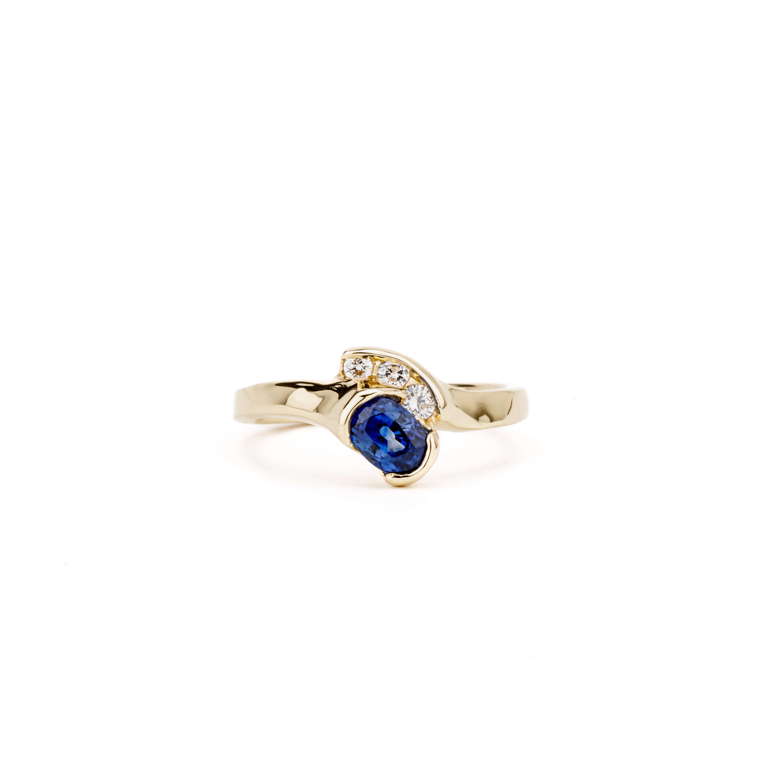 14K yellow gold bypass ring with oval blue sapphire and three channel-set diamonds