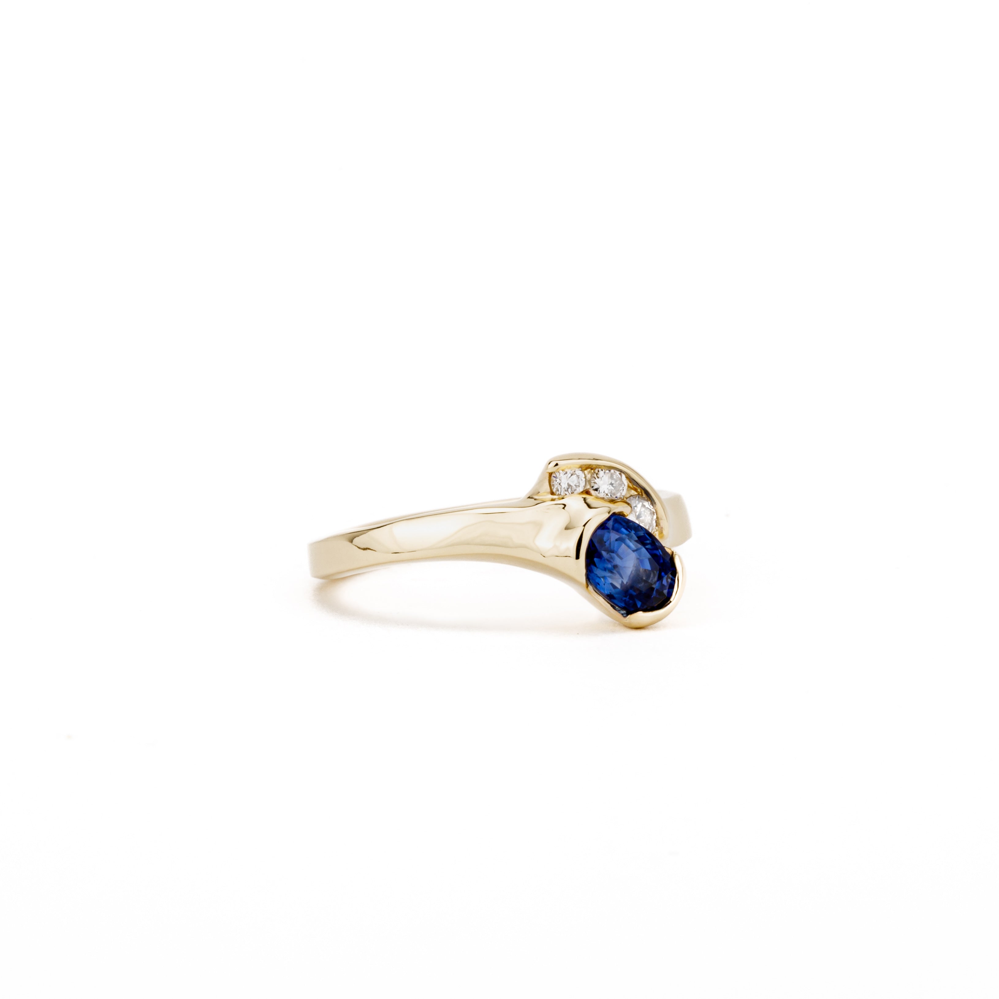 14K yellow gold bypass ring with oval blue sapphire and three channel-set diamonds