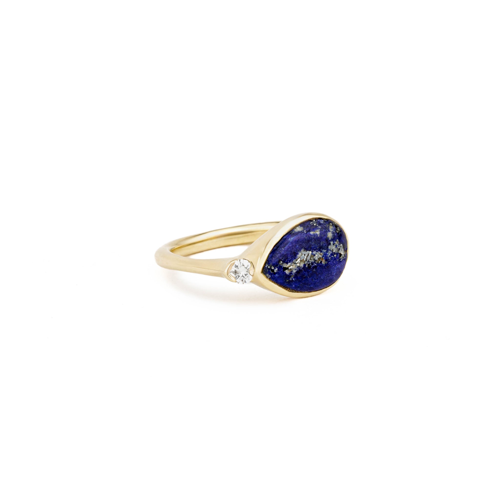 Yellow gold ring with a sideways pear-shaped lapis lazuli cabochon and a single round diamond accent.