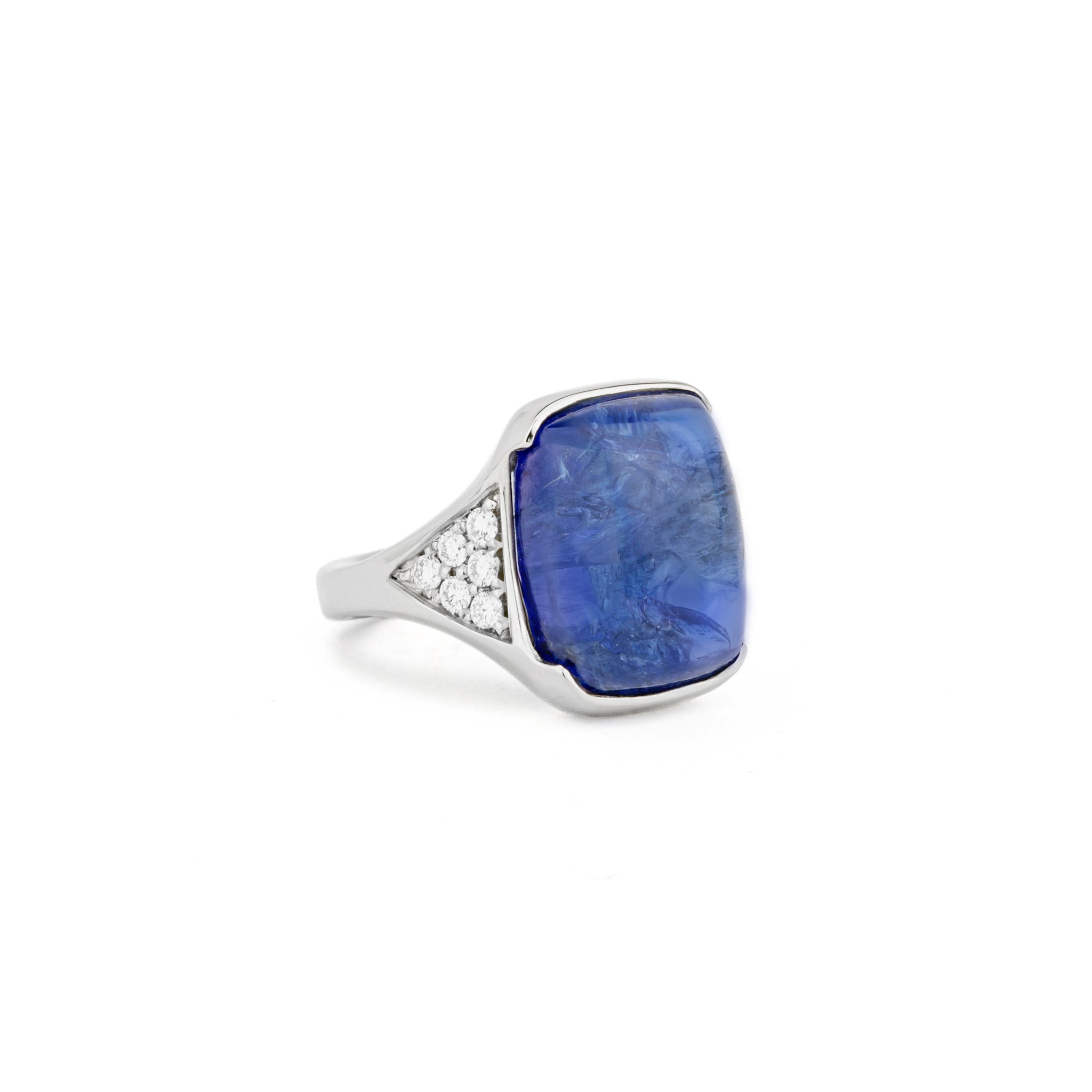 White gold ring with a large cabochon tanzanite in a hand-carved setting, flanked by pavé set diamond