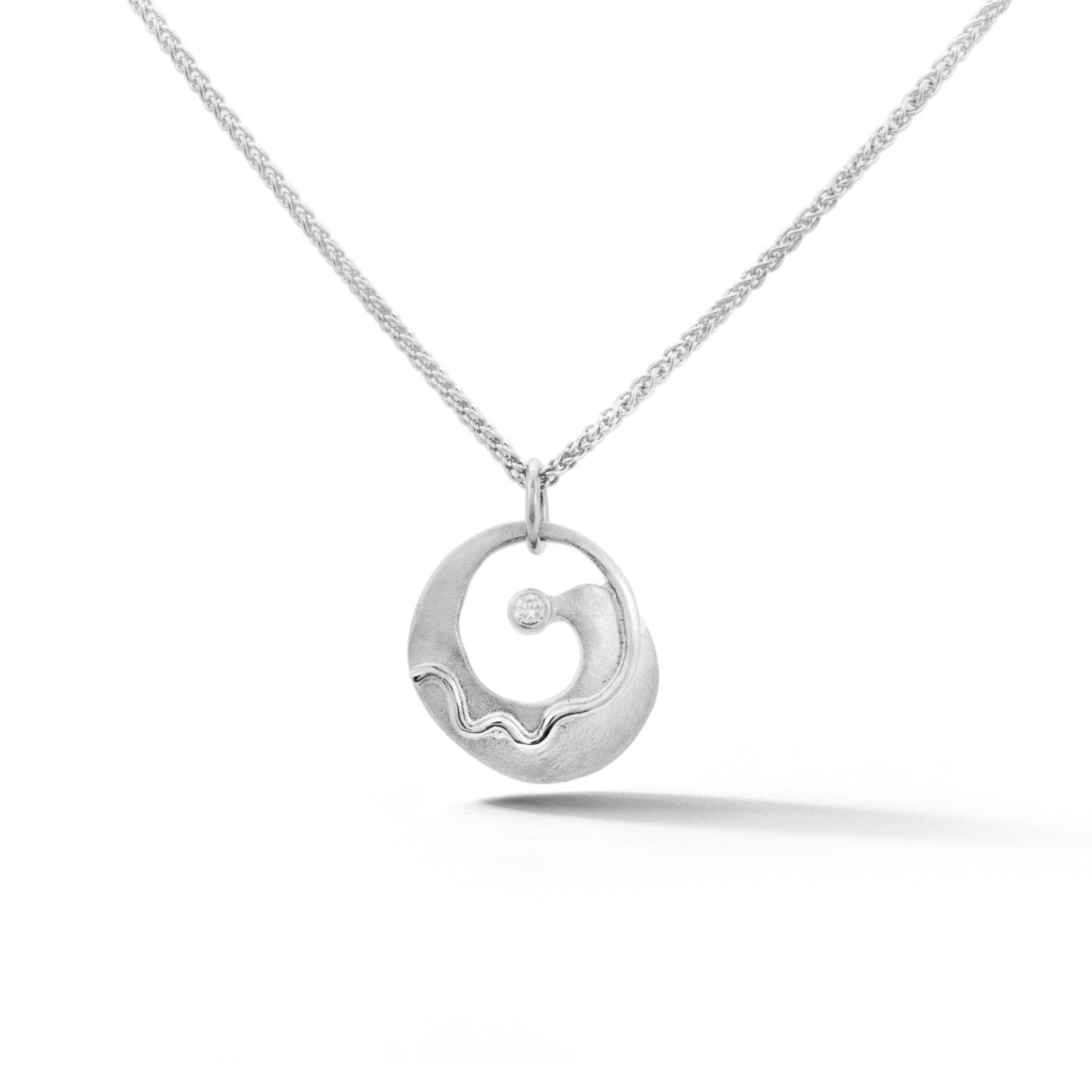 White gold circular pendant with spiral wave design and bezel set diamond