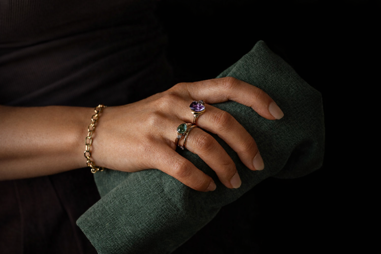 Hand wearing a purple sapphire ring and a moonstone ring designed by deJonghe Jewelry