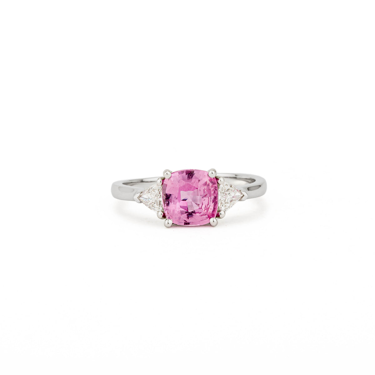 Platinum three-stone ring with cushion cut pink sapphire center stone and trillion cut diamond side stones