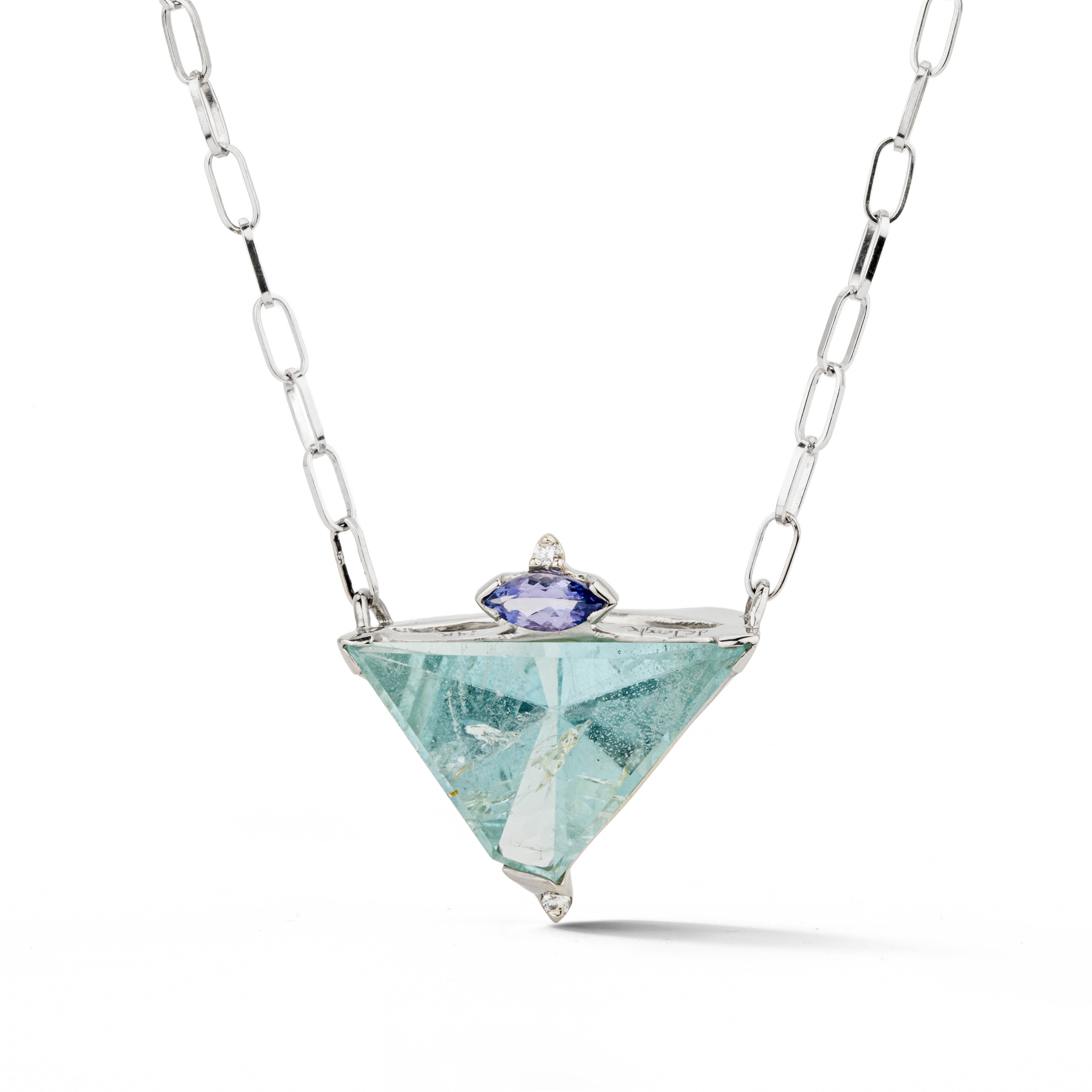 White gold necklace with a large trillion-cut aquamarine pendant accented by a marquise tanzanite and two diamonds, on an oval link chain.