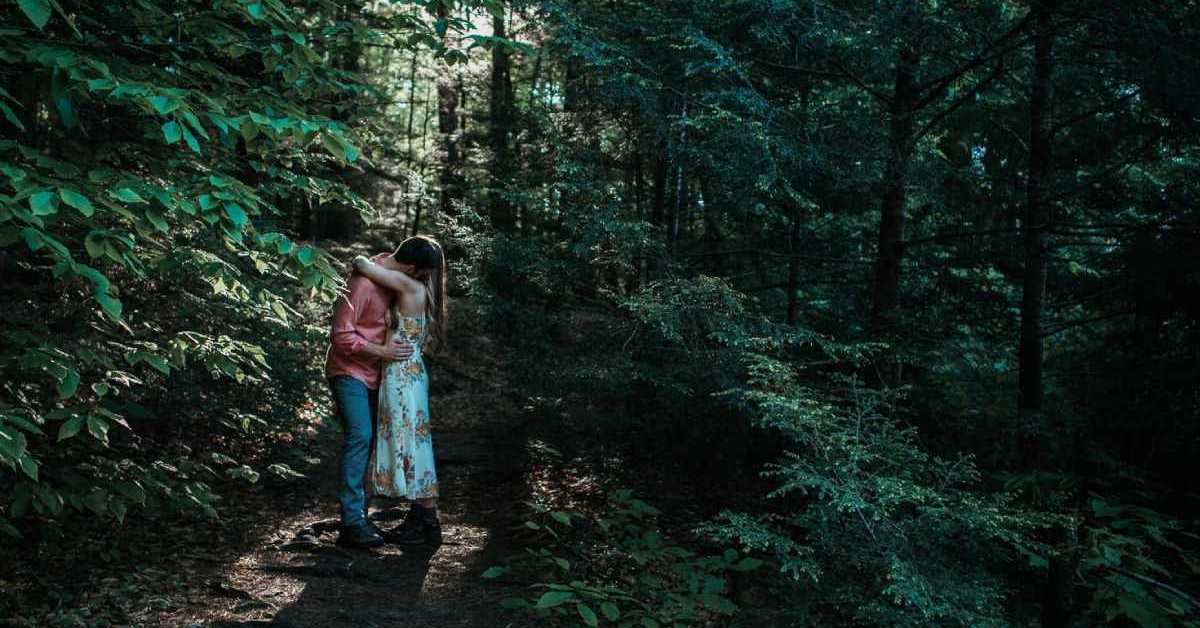 man and woman embracing in the woods