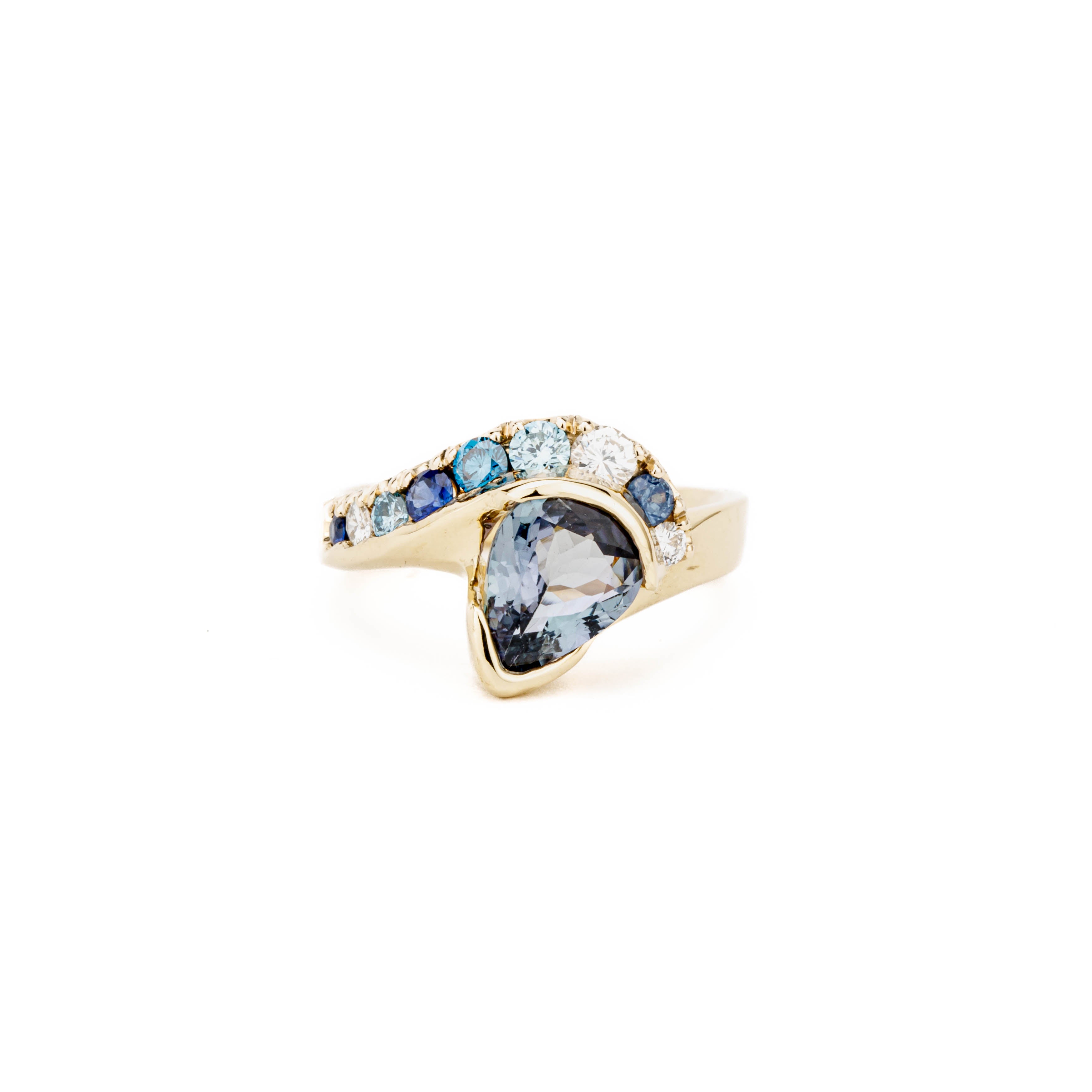 Custom one-of-a-kind 14k yellow gold ring featuring a customer's pear-shaped tanzanite with a sweeping arc of sapphires, color-enhanced diamonds, and white diamonds in channel and pavé settings