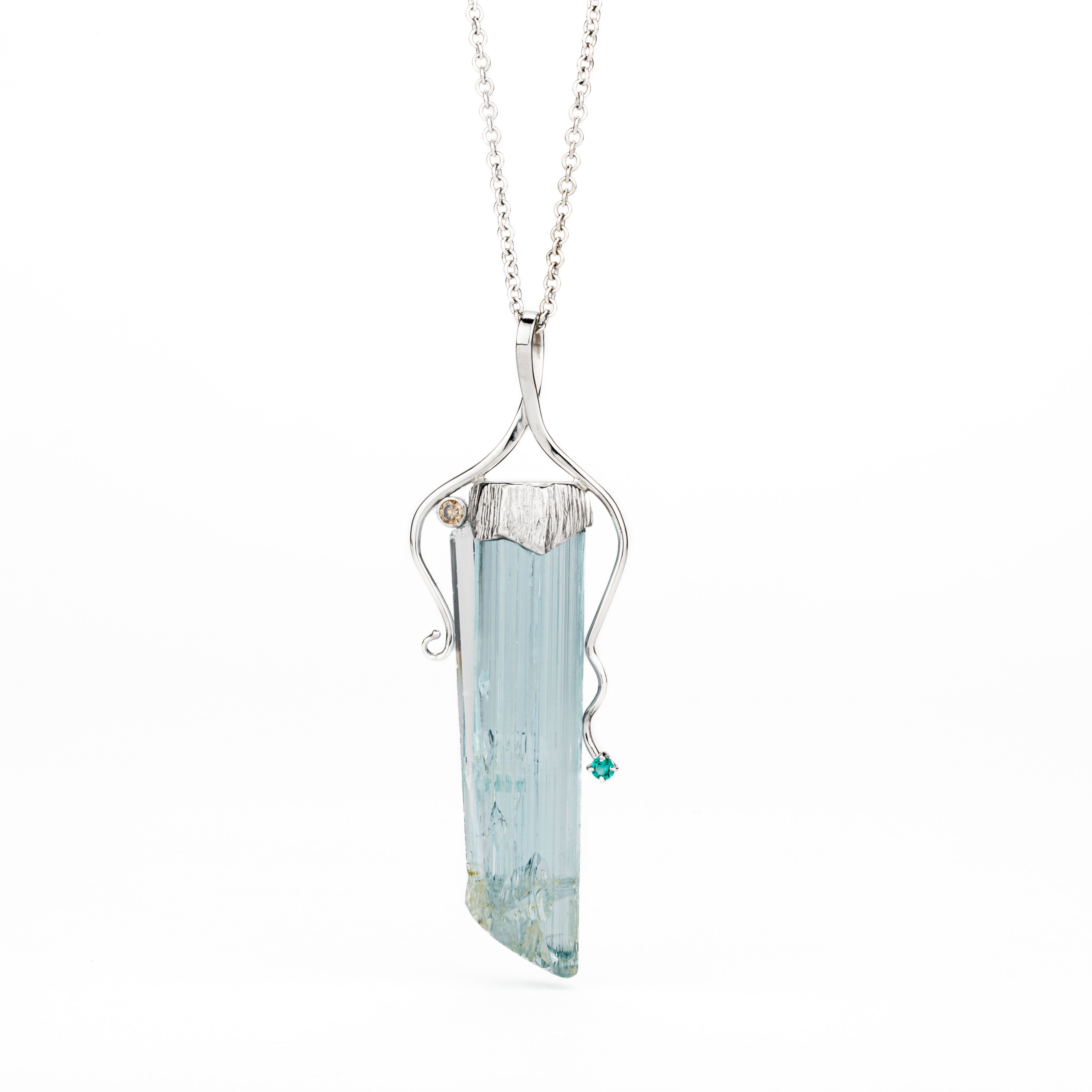 One-of-a-kind platinum pendant featuring a customer's cut and polished aquamarine crystal in a hand-carved cap with flowing tendrils, accented by a bezel-set champagne diamond and prong-set emerald