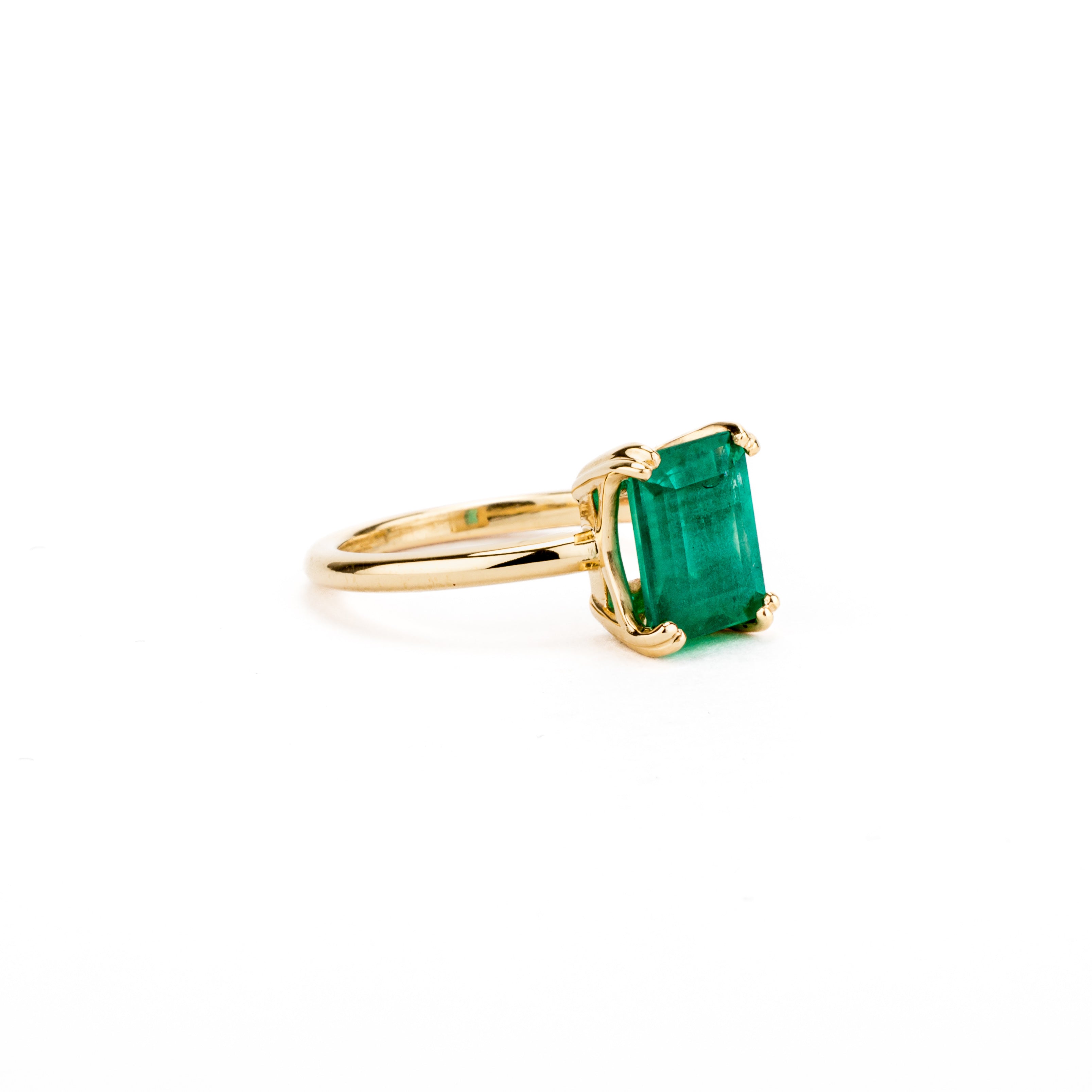 Double prong gold engagement ring featuring an emerald