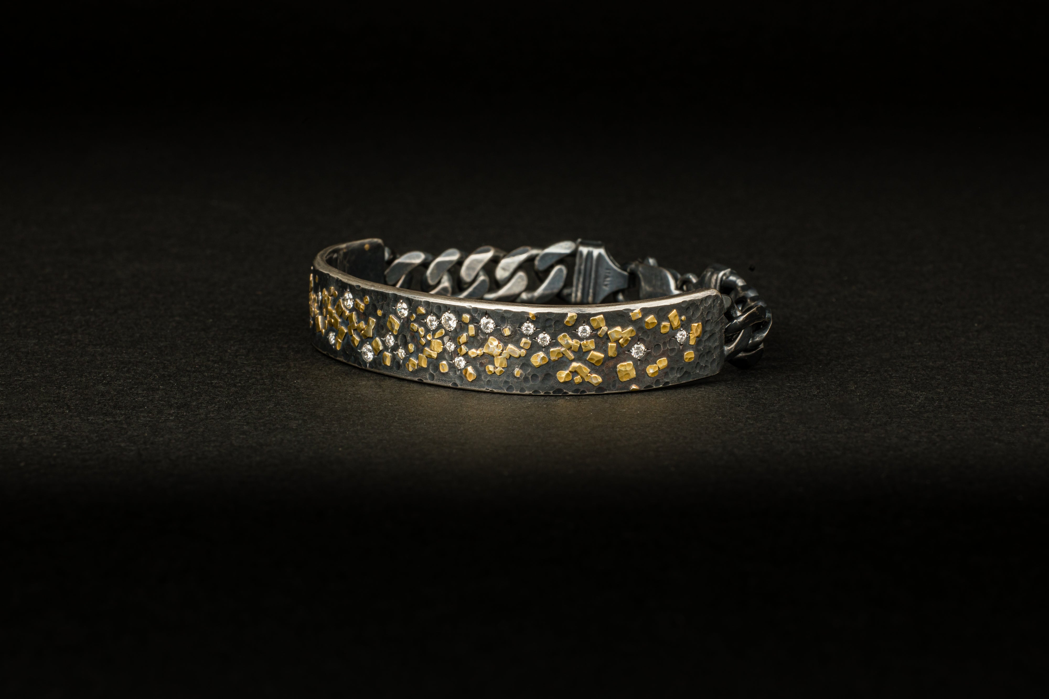  Men's oxidized sterling silver cuff bracelet with scattered 22k yellow gold fragments and round diamond accents, attached to a dark curb chain