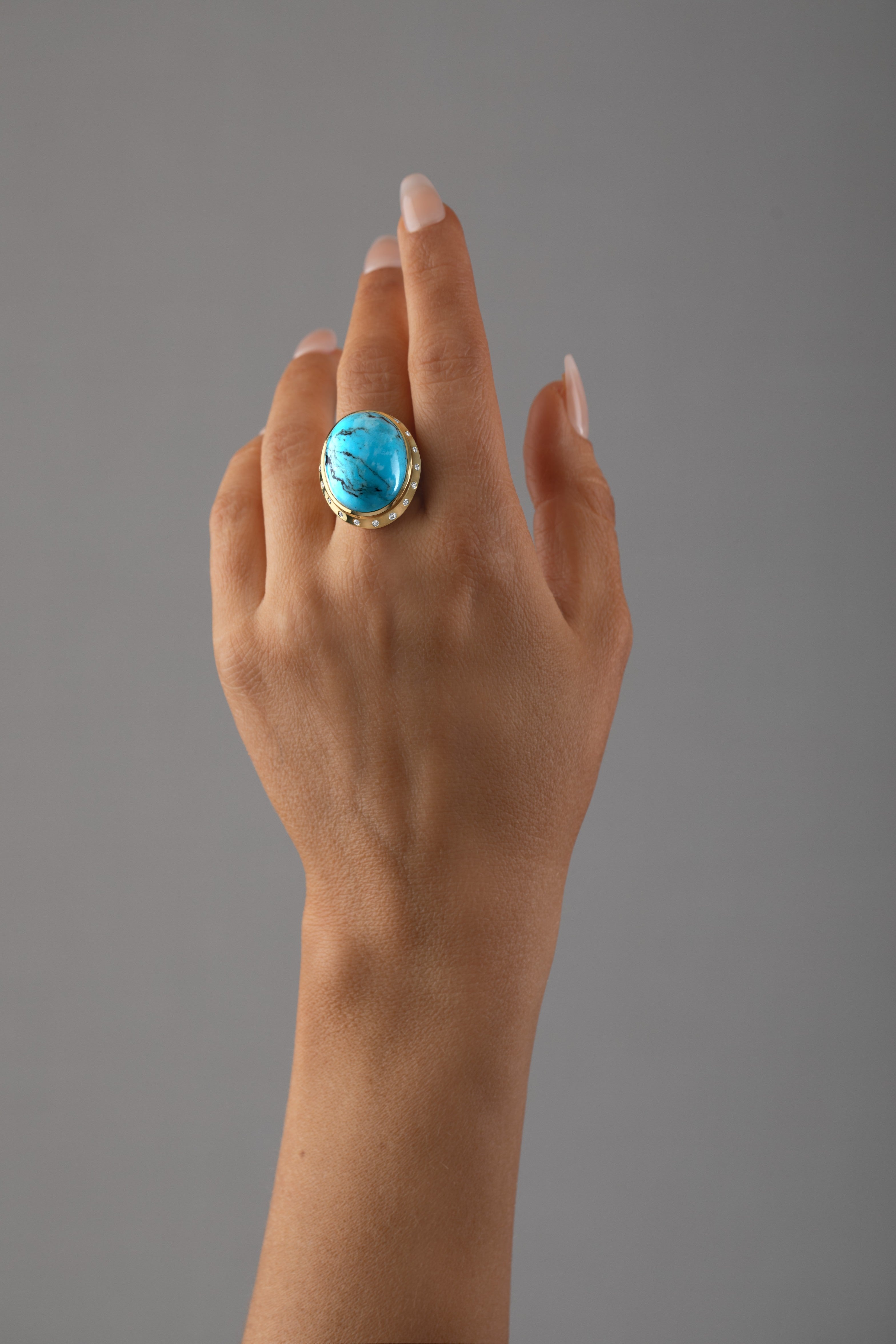 Hand wearing a turquoise and diamond ring in 14k yellow gold crafted by deJonghe Original Jewelry