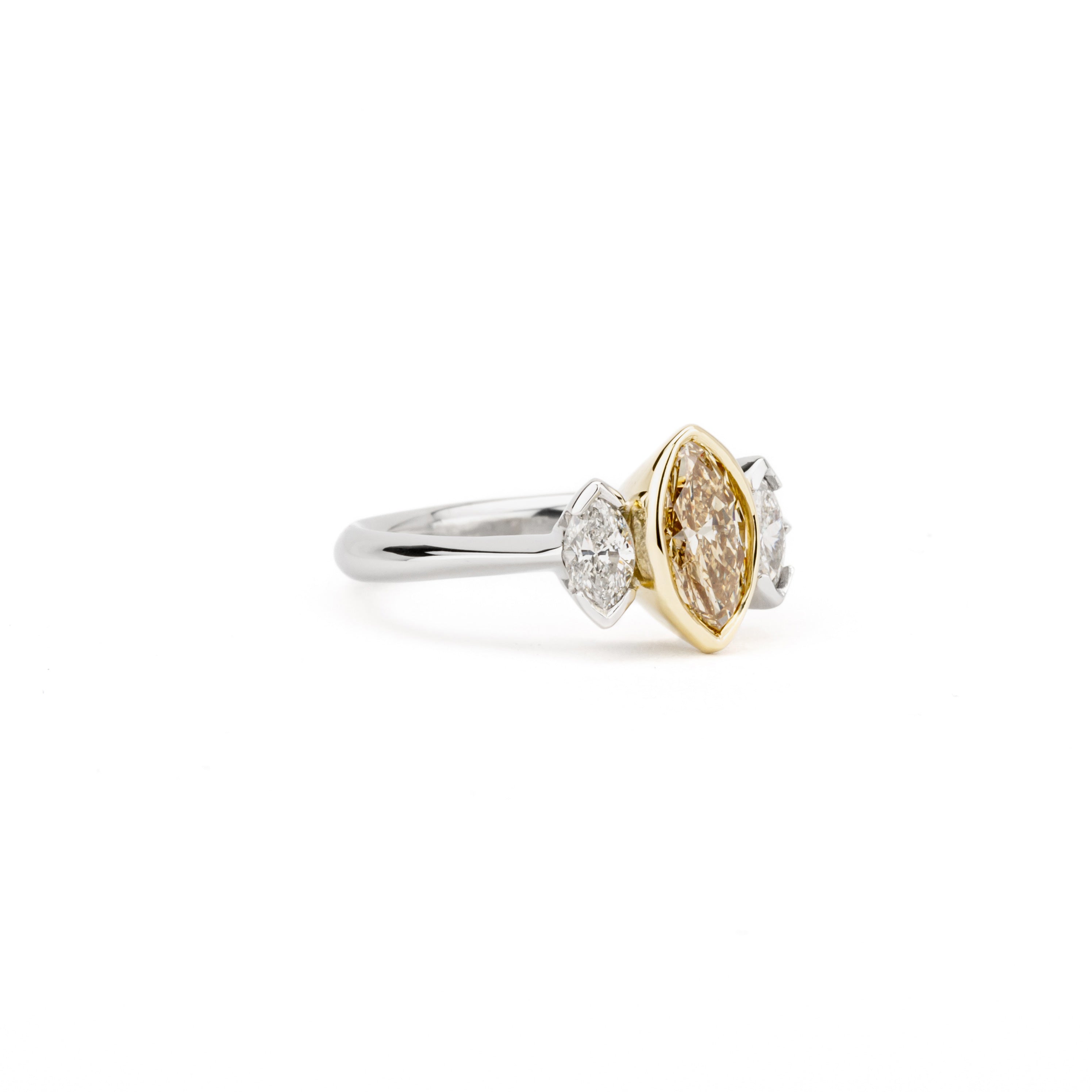 Platinum and 18K yellow gold three stone ring with fancy champagne marquise diamond center and white marquise diamond side stones
