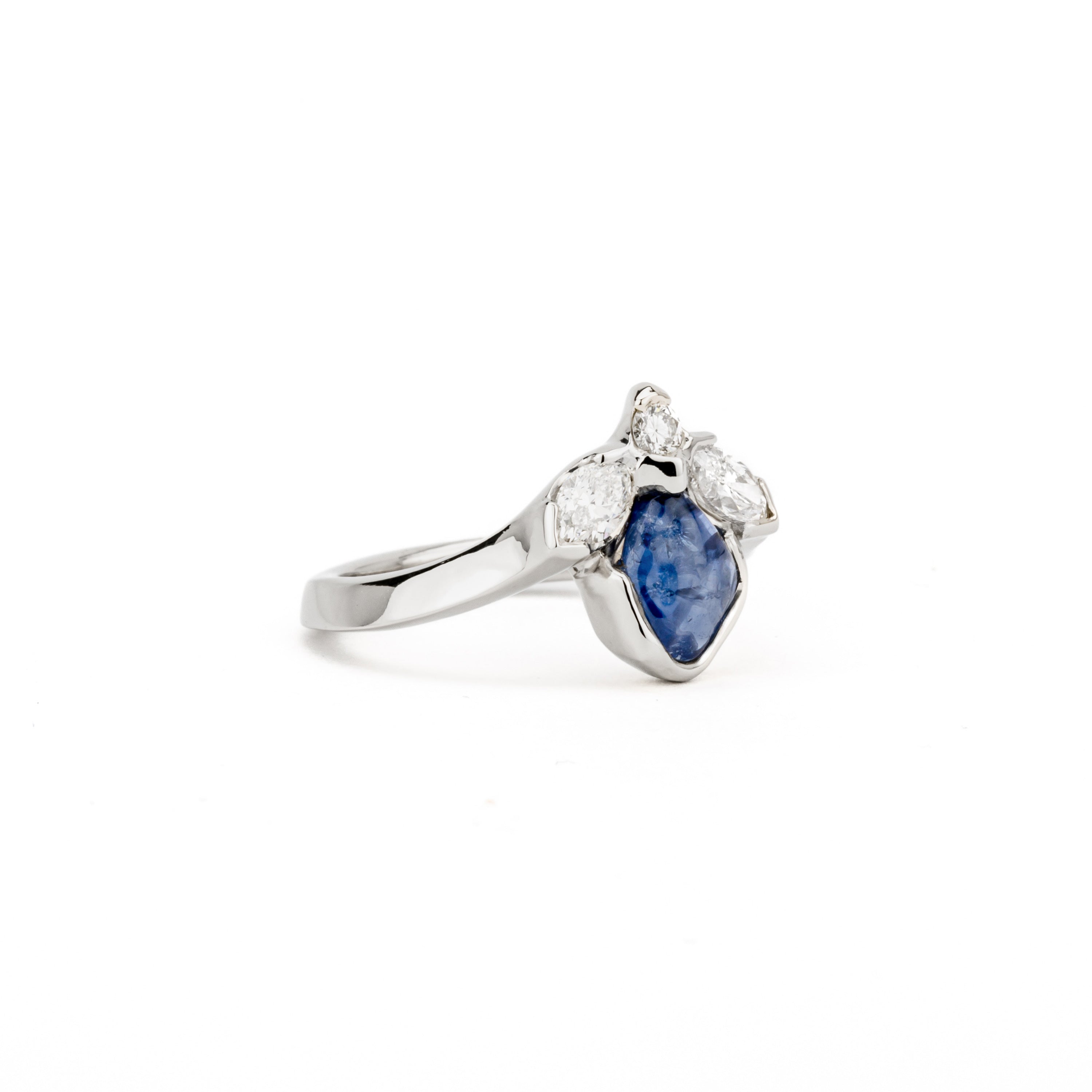 Freeform blue sapphire ring with marquise and round diamonds in white gold bezel setting
