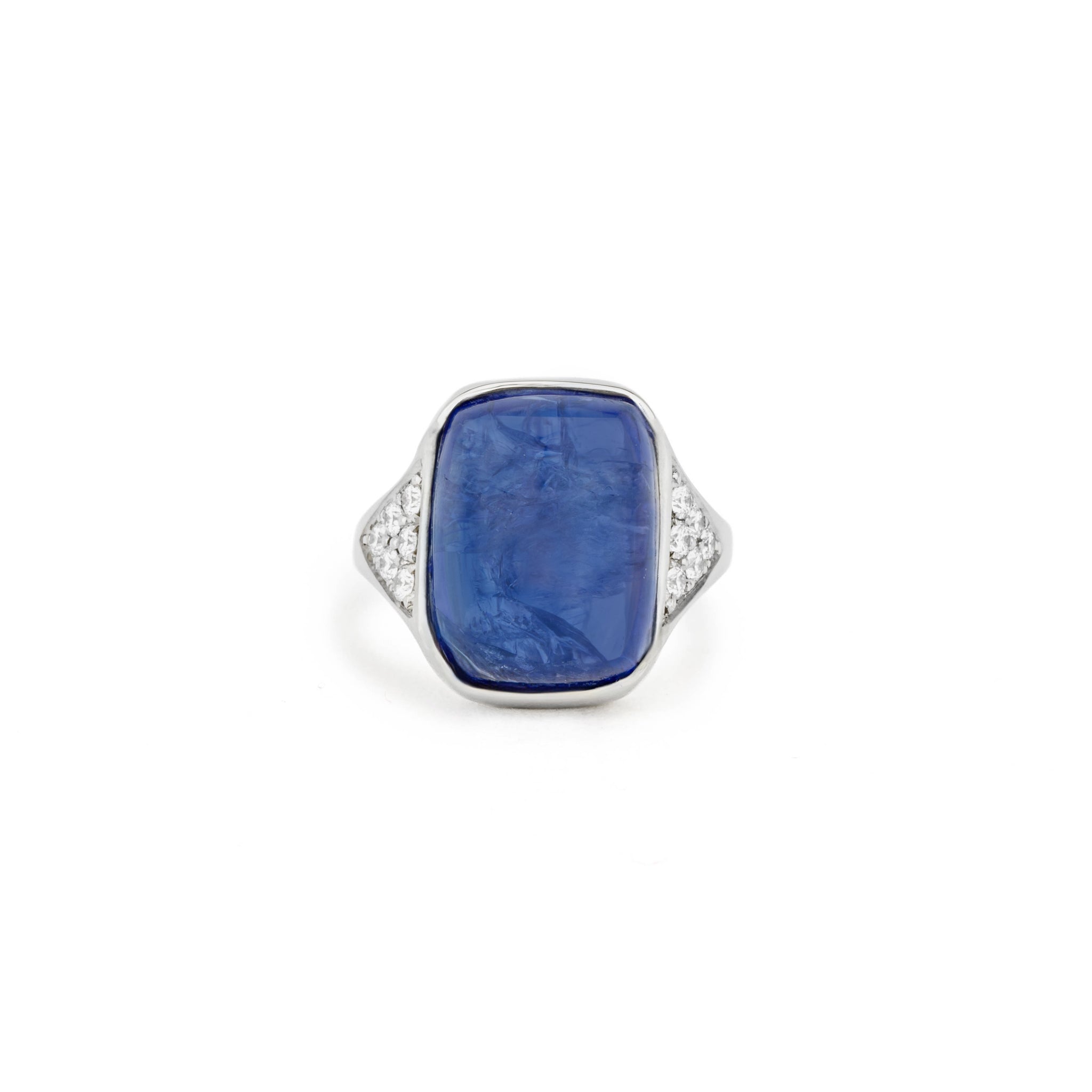 White gold ring with a large cabochon tanzanite in a hand-carved squared setting, flanked by pavé diamond shoulders