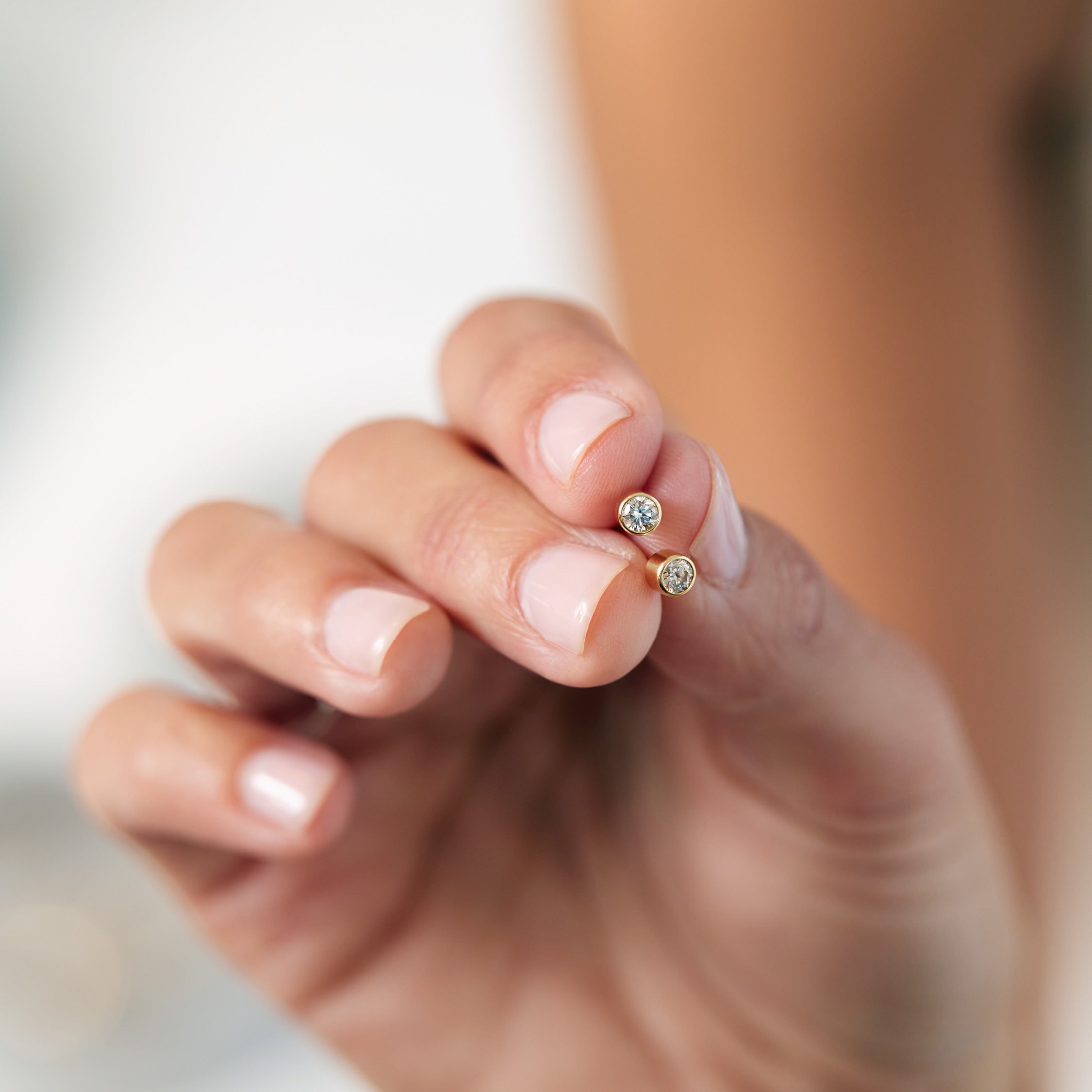 Hold bezel set diamond studs in a hand