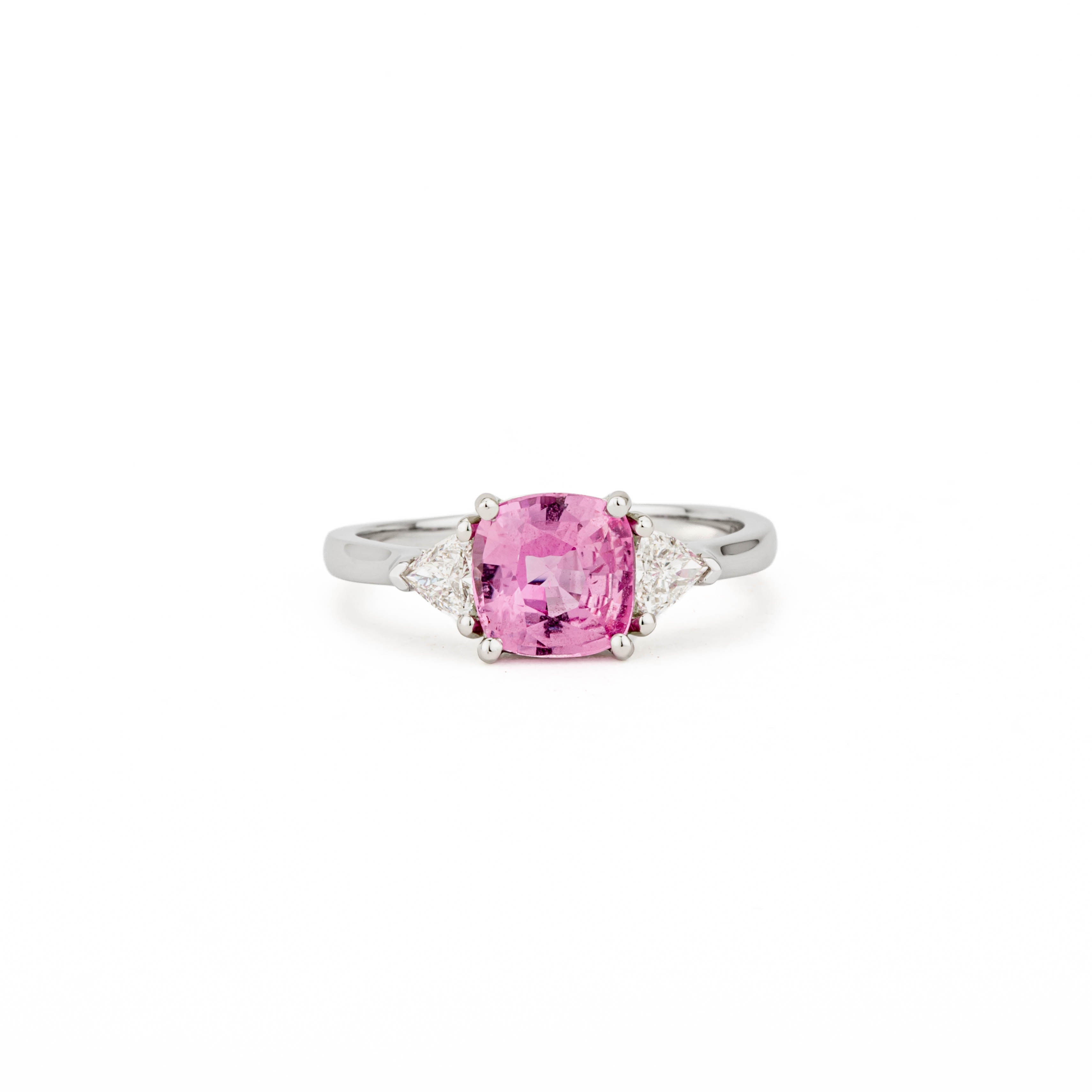 Platinum three-stone ring with cushion cut pink sapphire center stone and trillion cut diamond side stones