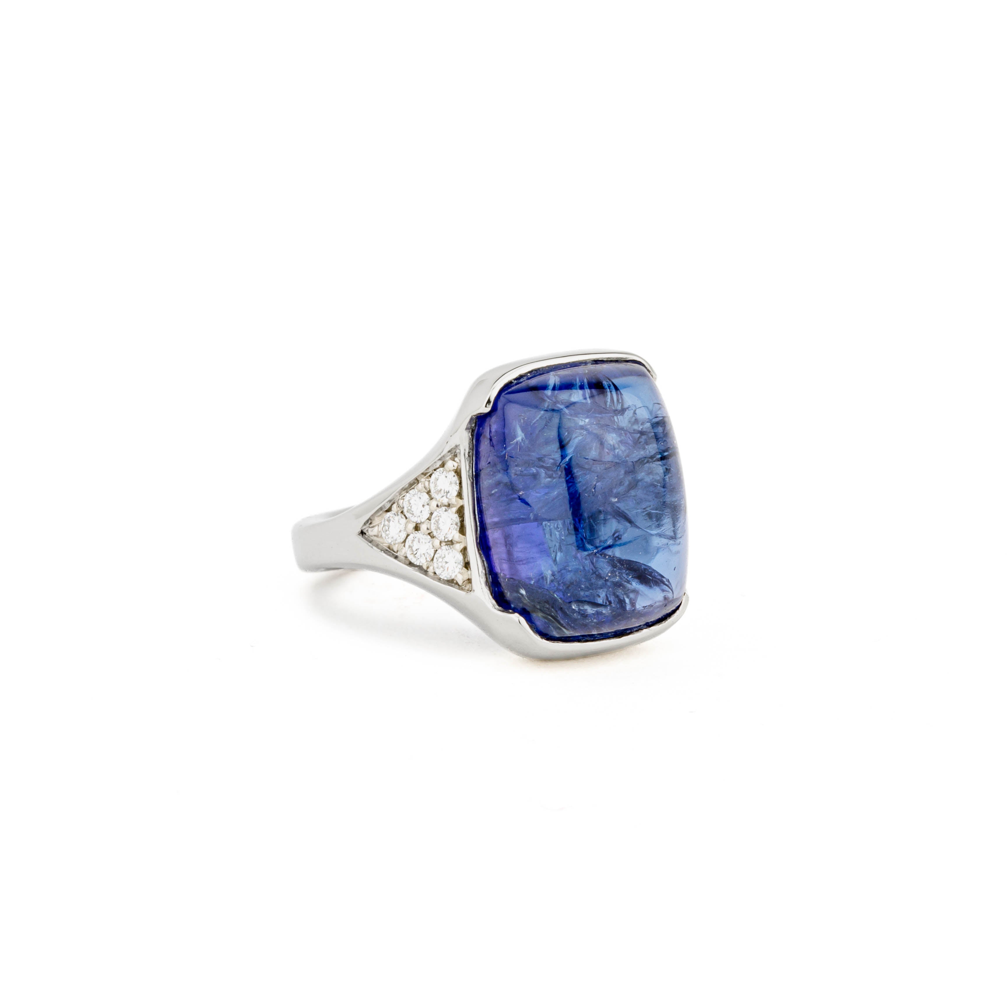 White gold ring with a large cabochon tanzanite in a hand-carved squared setting, flanked by pavé diamond shoulders
