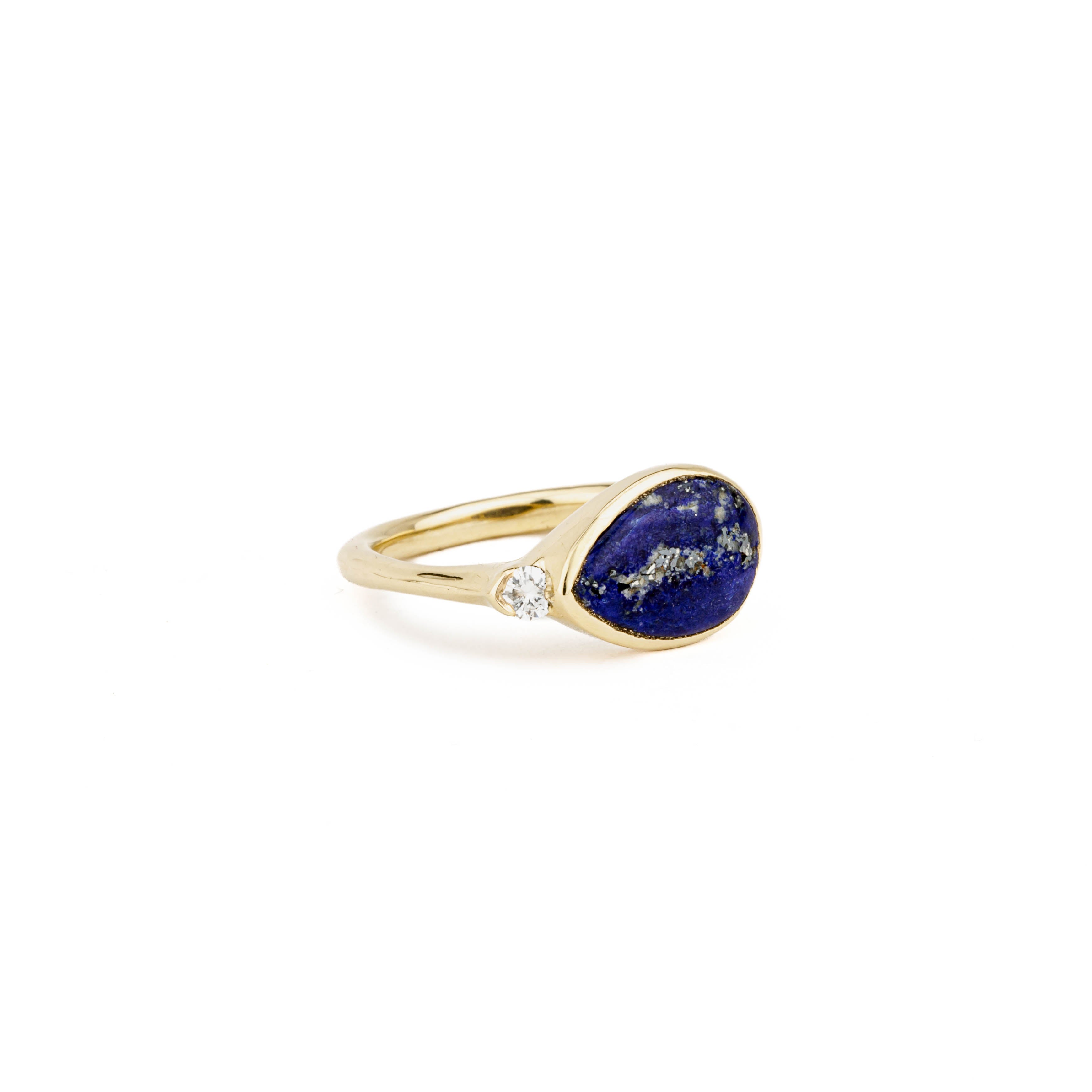 Yellow gold ring with a sideways pear-shaped lapis lazuli cabochon and a single round diamond accent.