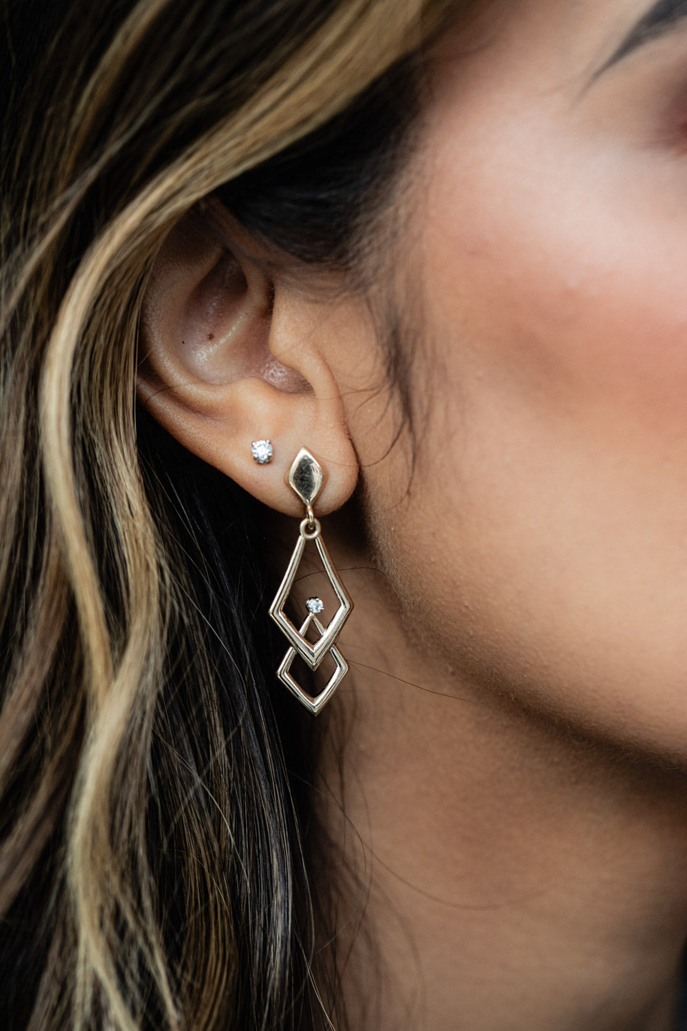 Yellow gold chevron drop earrings with diamond accents and geometric open frame design with post backs