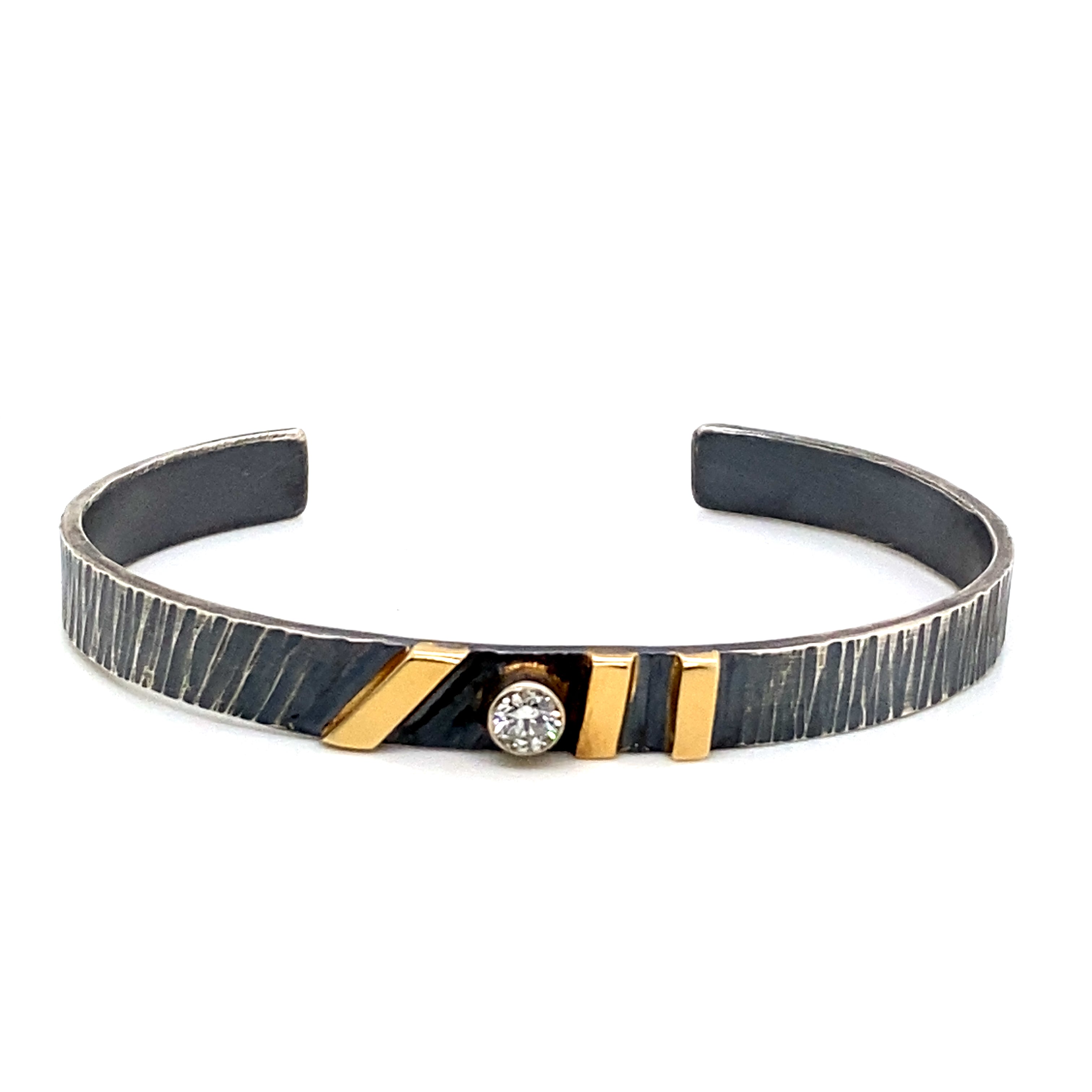 Men's oxidized sterling silver cuff bracelet with linear texture, three 14k yellow gold bar accents, and bezel-set 0.25ct diamond center
